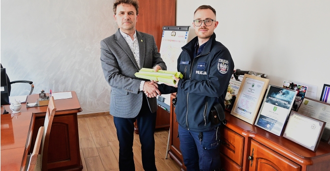 dwóch mężczyzn w tym policjant podaje sobie dłonie i trzymaja odblaski