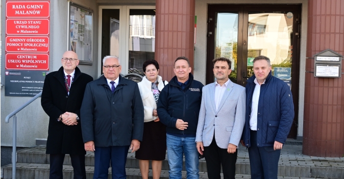grupa osob stojaca przed budynkiem urzedu gminy